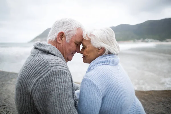 Senior couple sitting on rock at beach — Stock Photo, Image