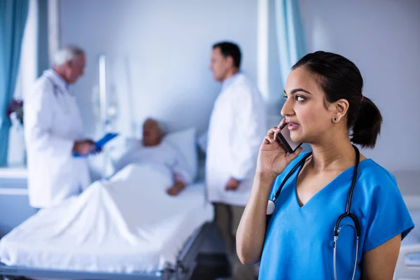 Kvinnliga läkare talar i en mobiltelefon i församlingen — Stockfoto