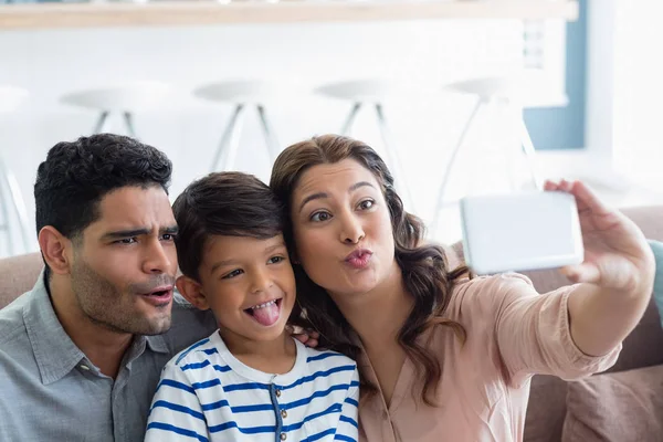 Föräldrar och son tar en selfie från mobiltelefon i vardagsrum — Stockfoto