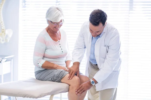 Fisioterapeuta dando terapia no joelho para a mulher idosa — Fotografia de Stock