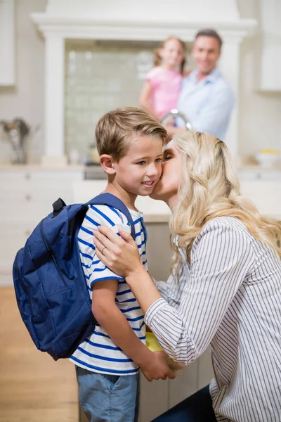 Женщина целует его сына во время посещения школы — стоковое фото