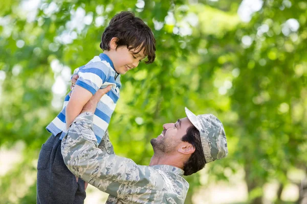 Army soldier lifting boy — Stock Photo, Image