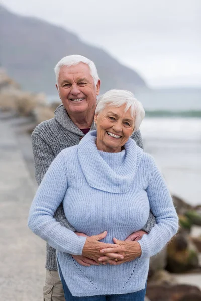Старшая пара обнимает друг друга на пляже — стоковое фото