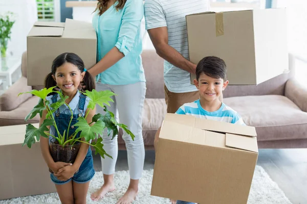 Ouders en kinderen houden van kartonnen dozen in woonkamer — Stockfoto