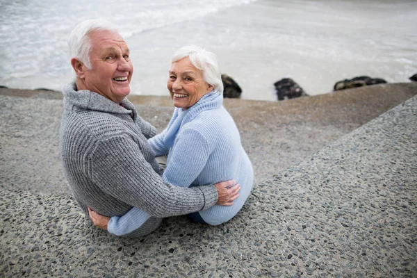 Senior paar zittend op rock op strand — Stockfoto