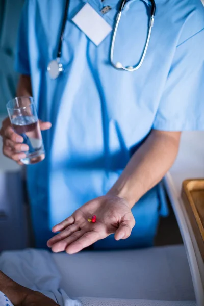 Ärztin serviert Seniorin Medikamente auf dem Bett — Stockfoto