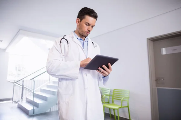 Doctor using digital tablet in corridor — Stock Photo, Image