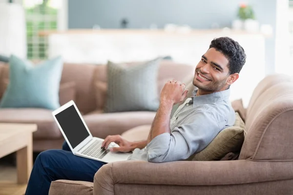 Mann sitzt auf Sofa und benutzt Laptop im heimischen Wohnzimmer — Stockfoto