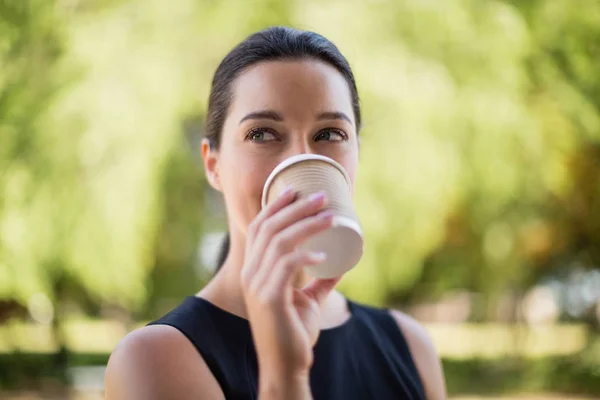 Tek kullanımlık fincandan kahve içen güzel bir kadın. — Stok fotoğraf