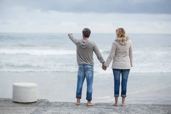 Casal de pé com as mãos dadas na praia — Fotografia de Stock