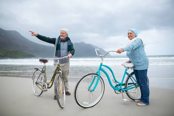 Couple aîné debout avec des vélos sur la plage — Photo