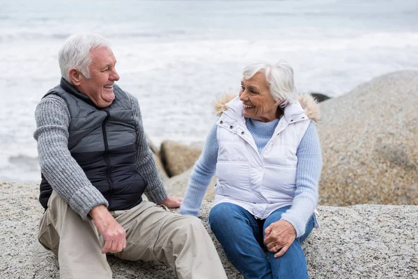 Seniorenpaar sitzt am Strand auf einem Felsen — Stockfoto