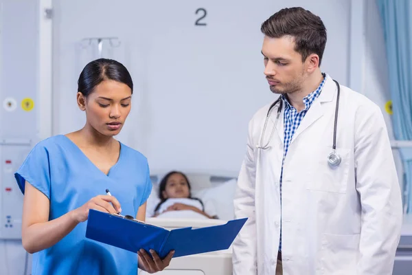 Krankenschwester und Arzt diskutieren über Klemmbrett — Stockfoto