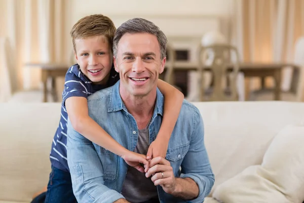 Sonriente hijo abrazando un padre en la sala de estar — Foto de Stock