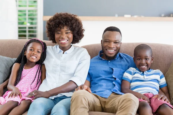 Retrato de padres e hijos sentados en un sofá en la sala de estar — Foto de Stock