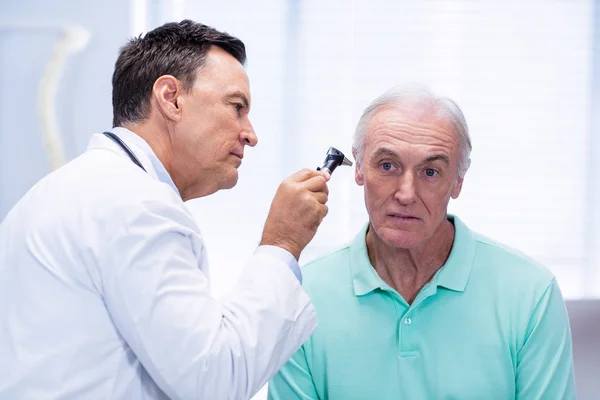 Врач осматривает ухо пациента с помощью отоскопа — стоковое фото