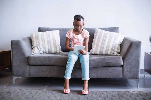 Девушка сидит на диване с помощью цифрового планшета — стоковое фото