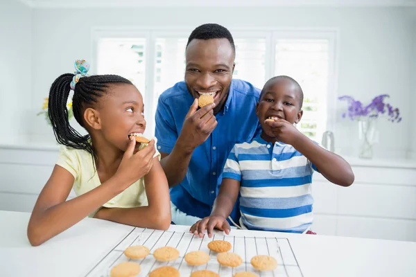 Vader en kinderen eten thuis cookies — Stockfoto