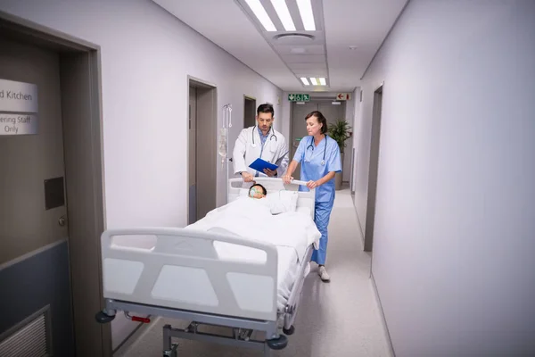 Medici che spingono letto barella di emergenza in corridoio — Foto Stock