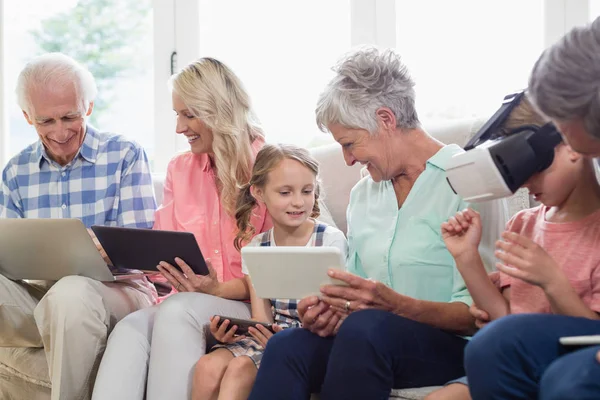 Oturma odasında dijital tablet, cep telefonu ve sanal kulaklık kullanarak çoklu nesil aile — Stok fotoğraf