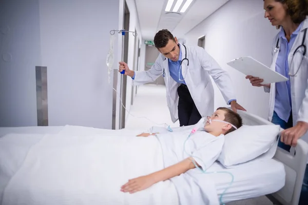 Médico ajustando IV gotejamento enquanto o paciente deitado na cama — Fotografia de Stock