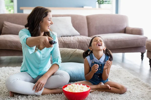 Мати і дочка дивиться телевізор, маючи попкорн у вітальні — стокове фото