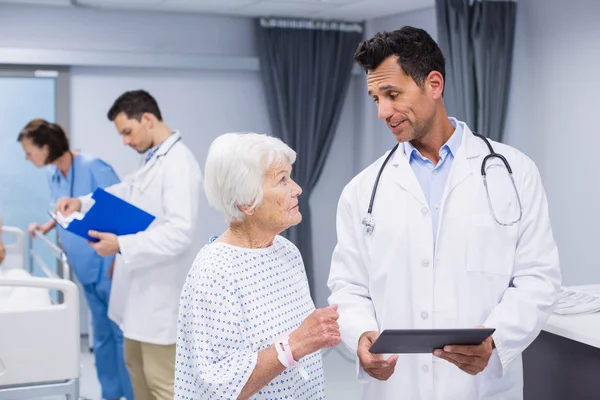 Arts in gesprek met senior patiënt tijdens het gebruik van digitale tablet — Stockfoto