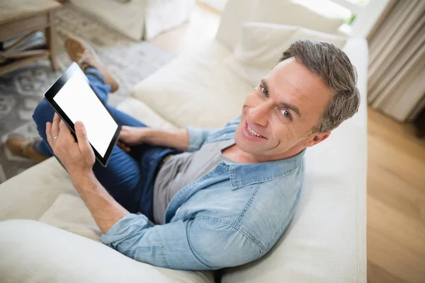Adam kanepede oturan ve oturma odasında dijital tablet kullanma — Stok fotoğraf