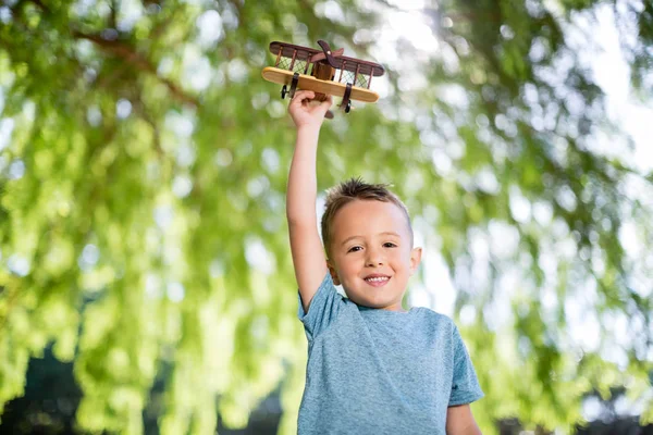 Retrato de menino brincando com um avião de brinquedo no parque — Fotografia de Stock