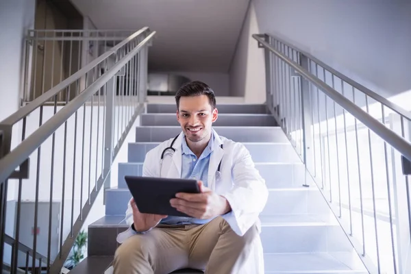 Портрет врача, сидящего на лестнице с помощью цифрового планшета — стоковое фото