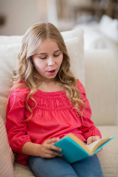Dziewczyna, czytając książkę na kanapie w salonie — Zdjęcie stockowe