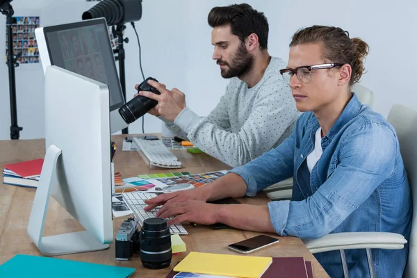 Photographers working together at desk — Stock Photo, Image