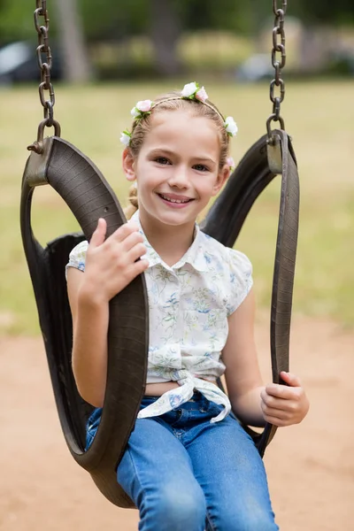 Gelukkig meisje zit op een schommel in park — Stockfoto