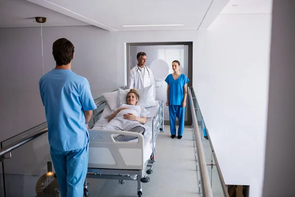 Team of doctors interacting with each other while examining pregnant woman — Stock Photo, Image