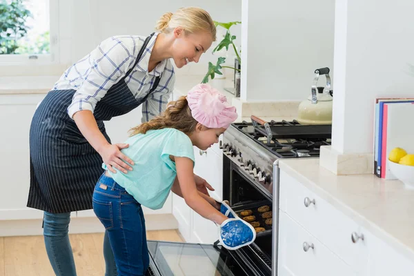 Moeder en dochter lade van cookies plaatsen in oven — Stockfoto