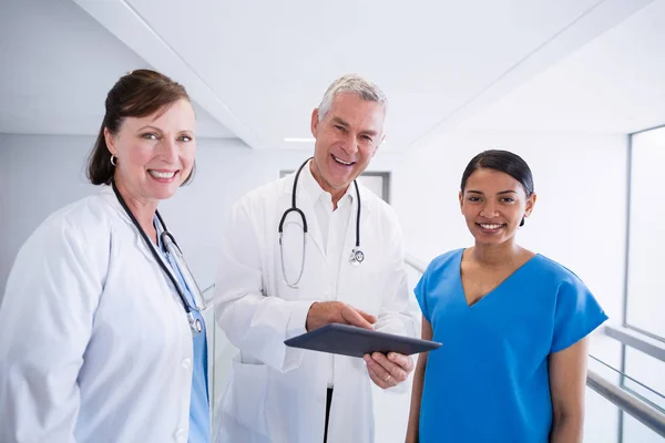 Retrato de enfermera sonriente y médicos discutiendo sobre tableta digital — Foto de Stock