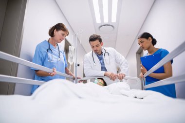 Doctors examining patient in corridor  clipart
