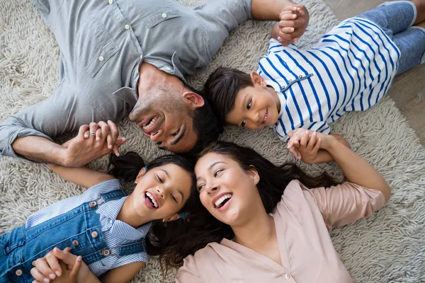 Lycklig familj interagerar liggande på matta — Stockfoto