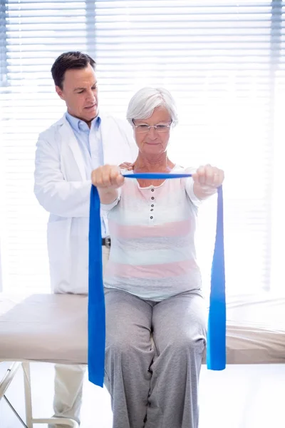 Мужской физиотерапевт делает массаж плеч пожилой женщине — стоковое фото
