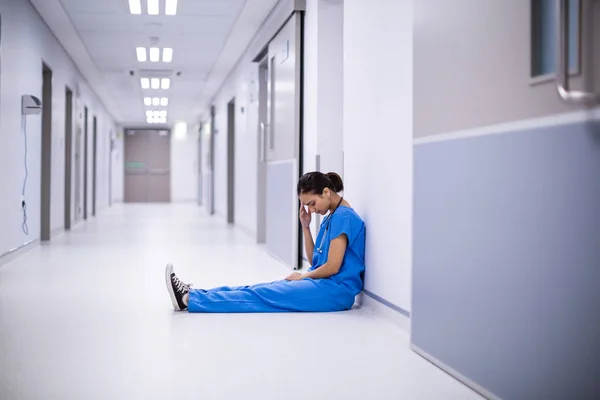 Médica tensa sentada no corredor — Fotografia de Stock