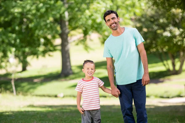 Son holding hands of his father in park — Stock Photo, Image