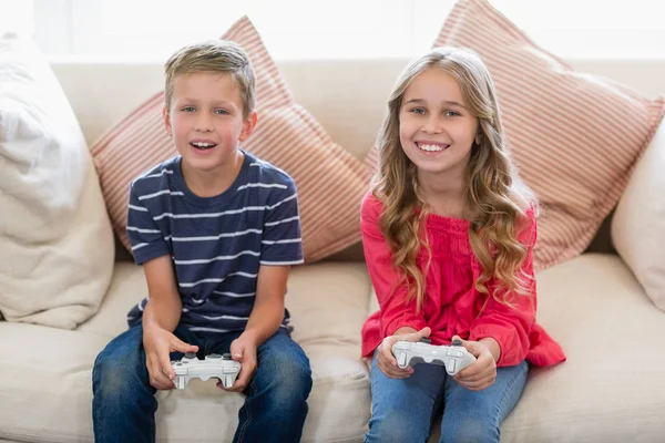 Frères et sœurs jouant à des jeux vidéo dans le salon — Photo