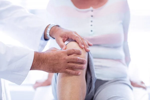Physiothérapeute donnant une thérapie du genou à une femme âgée — Photo