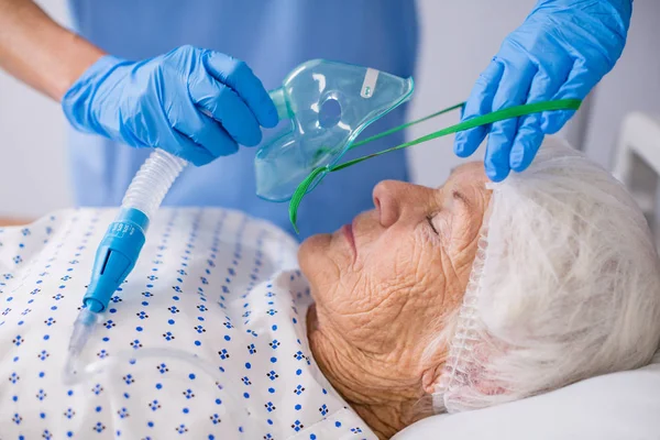 Doctor putting an oxygen mask on patient — Stock Photo, Image