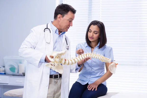 Fisioterapeuta explicando o modelo da coluna vertebral para o paciente — Fotografia de Stock