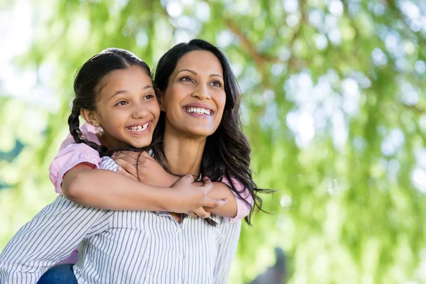 Happy mother giving piggyback ride to her daughter — Stock Photo, Image