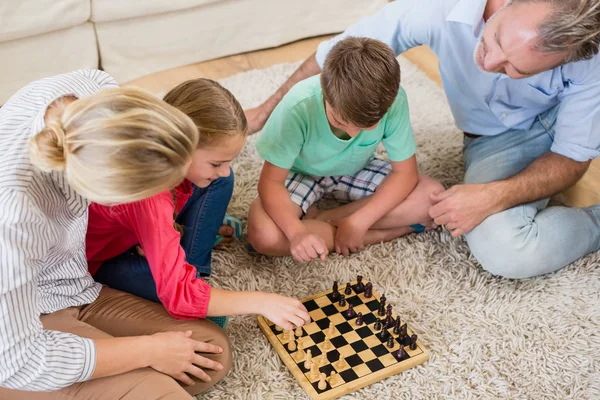 Família jogando xadrez juntos em casa na sala de estar — Fotografia de Stock