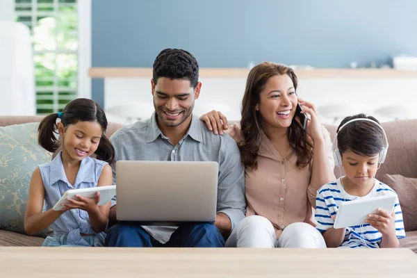 Föräldrar och barn med laptop och digitala tablett i vardagsrum — Stockfoto