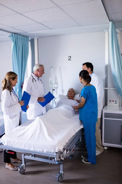 Team of doctors interacting with female senior patient — Stock Photo, Image