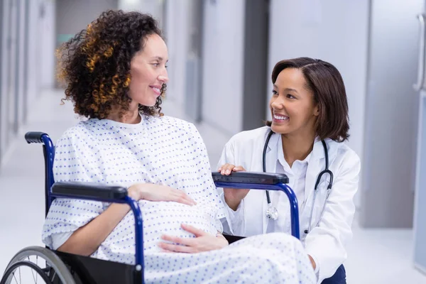 Doktor uklidňující těhotná žena v chodbě — Stock fotografie